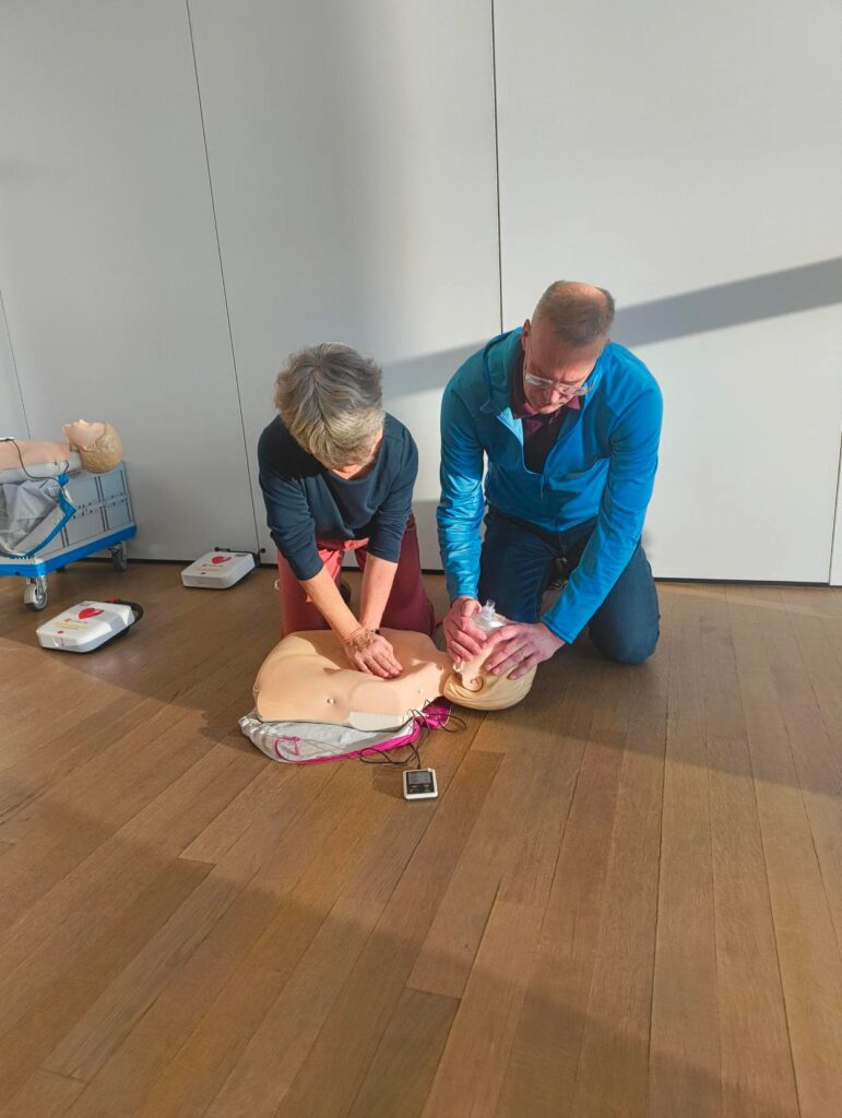 Ein Mann und eine Frau üben die Reanimation an einer Puppe. 