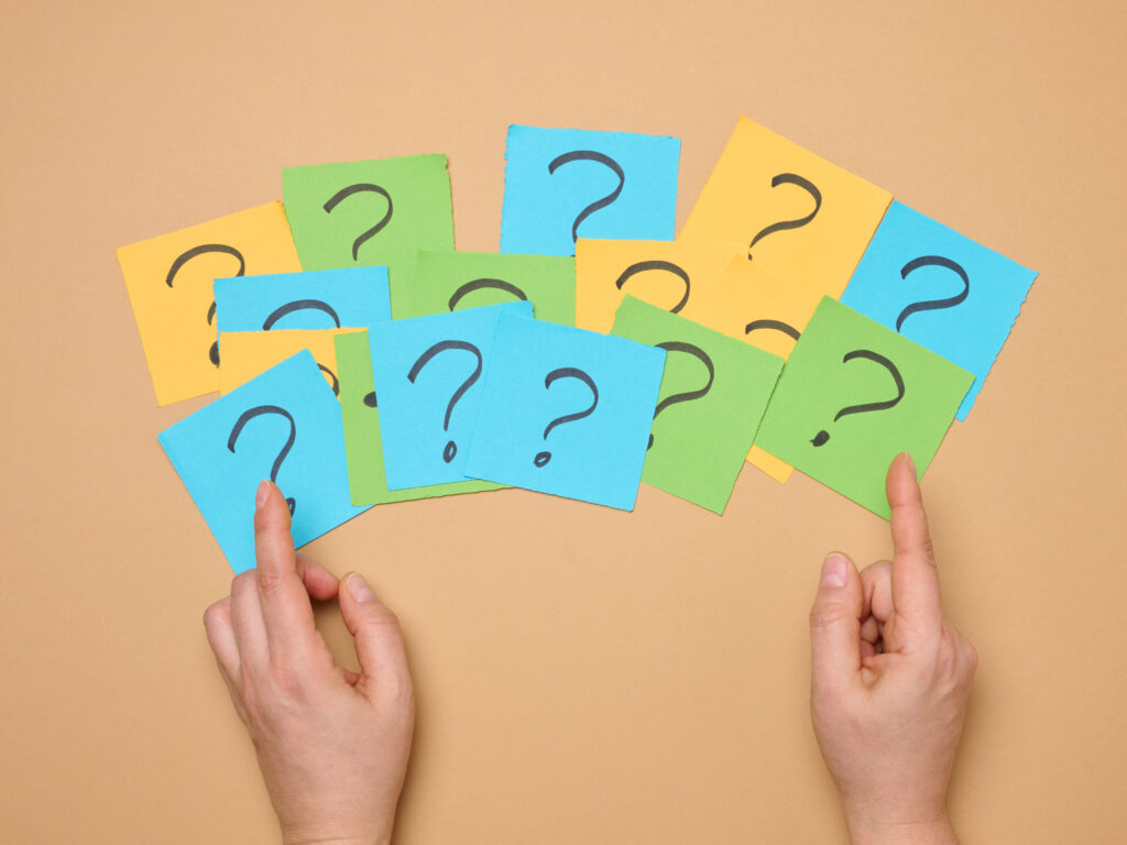 Female hands hold paper sheets with a drawn question mark on a beige background, searching for the answer and truth